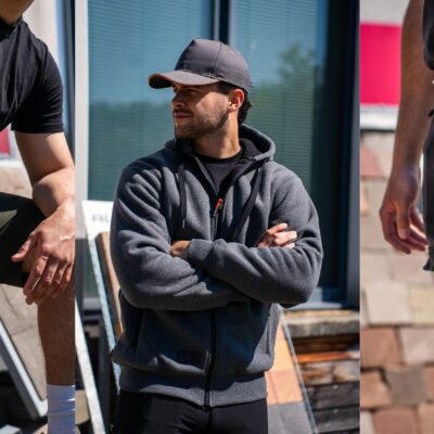 Trois hommes portent des vêtements de travail Herock® adaptés à l'été : bermuda de chantier kaki, sweat zippé gris foncé et pantalon technique noir avec poches renforcées.